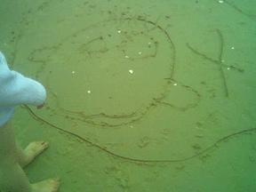 round smiley face drawn a little shakily in sand
